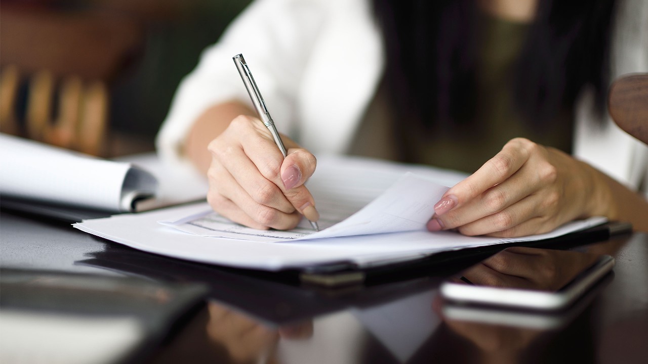 Hand signing contract; image used for Paper Form HKSAR Cash Payout Scheme 
